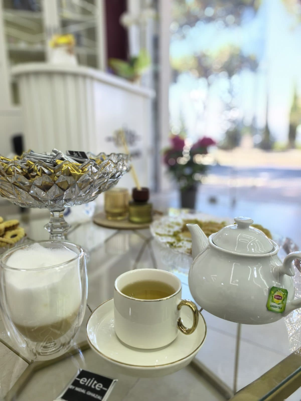 Coffee, green tea and sweets served on a glass table