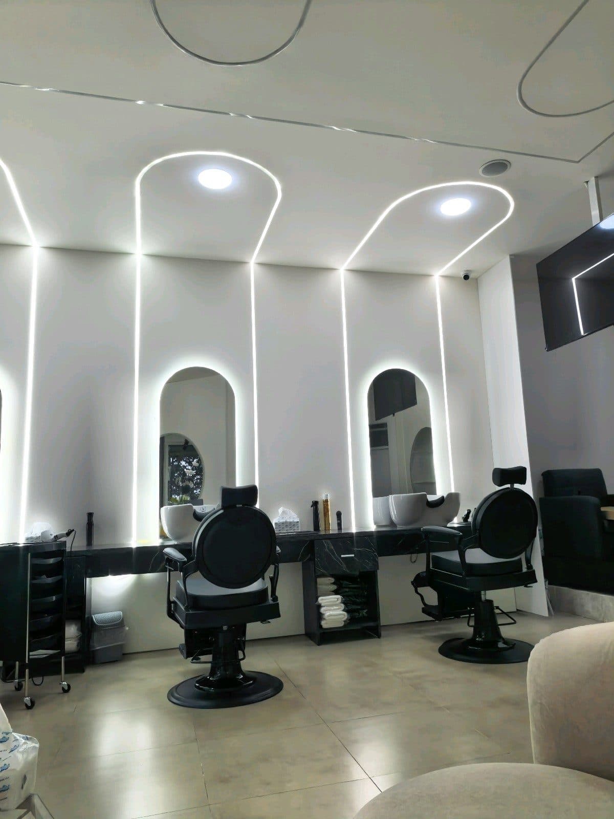 Black barber chairs beneath glowing arched mirrors at Elite Barber Shop
